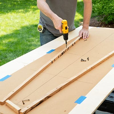 Wooden jig boards secured to work table with screws.