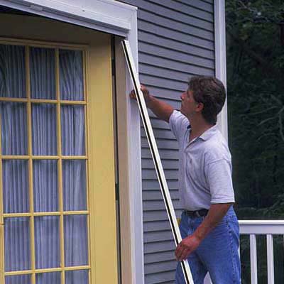 A man adjusts his retractable screen door.
