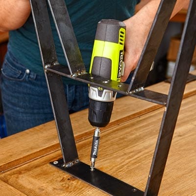 A person secures the table legs to the salvaged cabinet door.