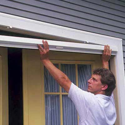 A man attaches the screen handle to his retractable screen door.