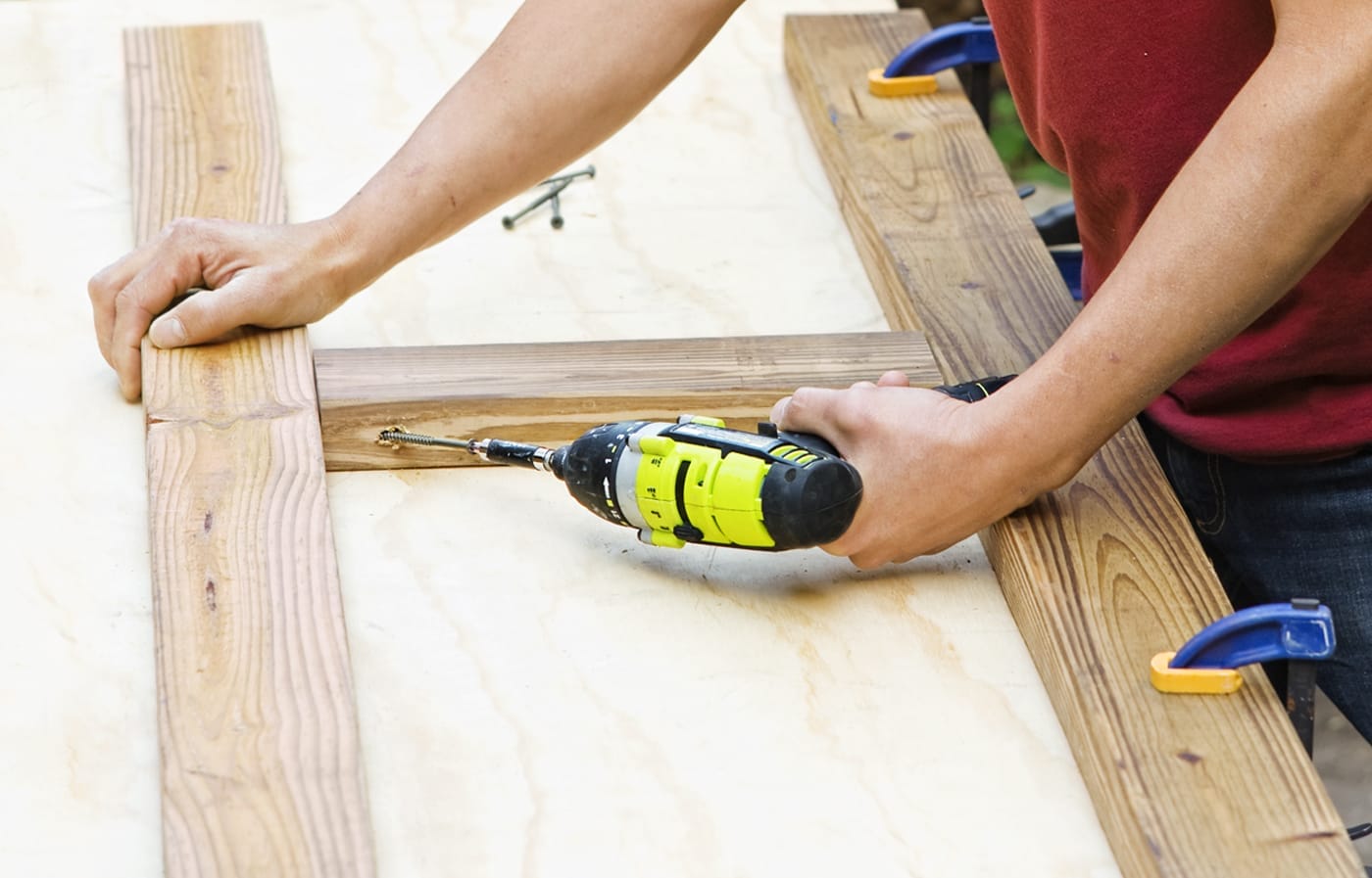 A person drills pieces of wood together to build the front and back frames for a privacy planter.