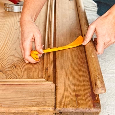 A person removes the astragal from a salvaged cabinet door to make it a coffee table.