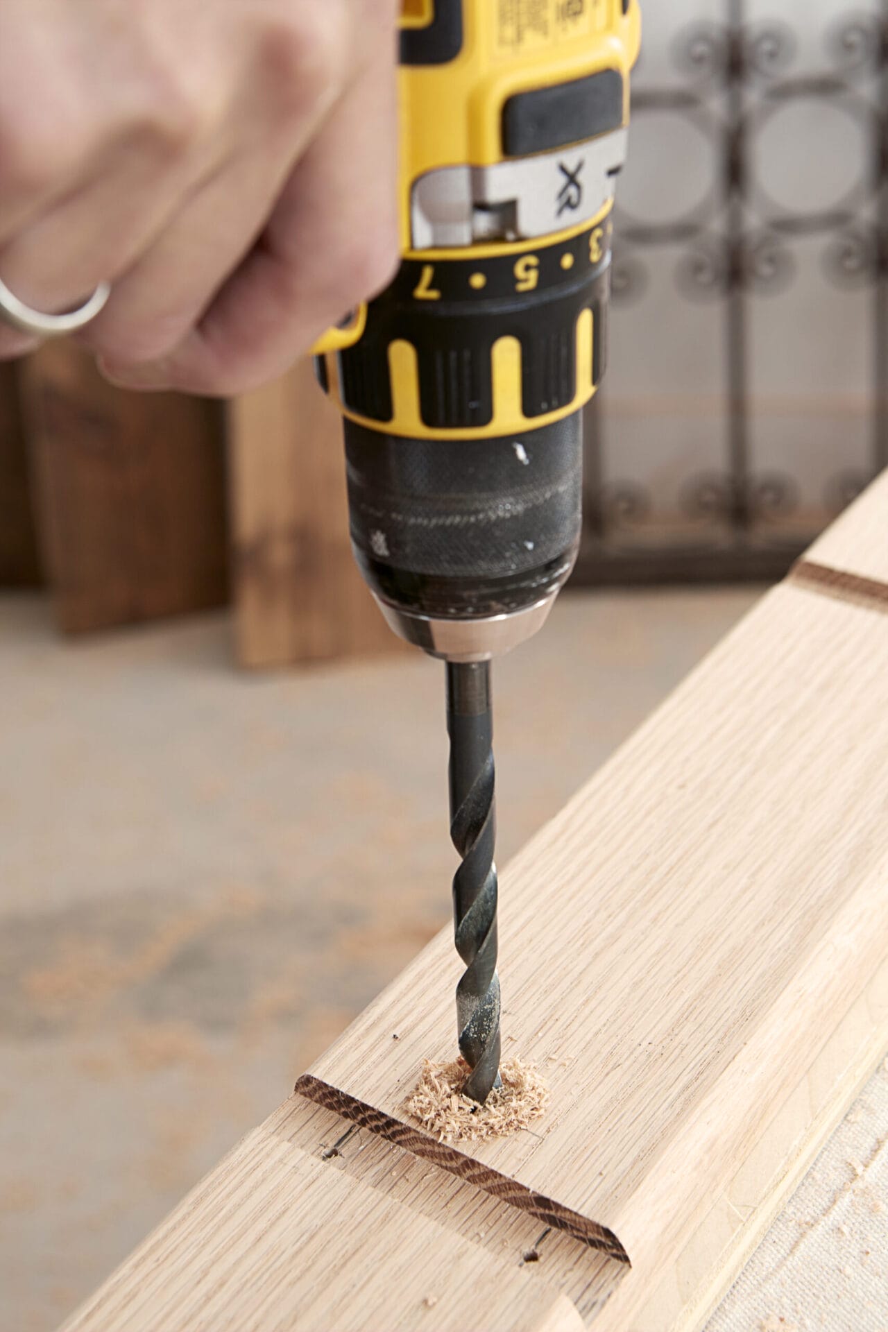 Image of a person completing a step in the DIY rolling library ladder project, which involves drilling pilot holes 