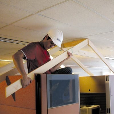 A man in a hard hat holds a 1x4 rafter