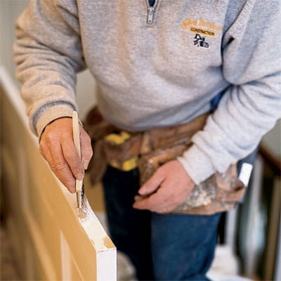 Tom Silva paints the raw wood edge after planing the sticking door