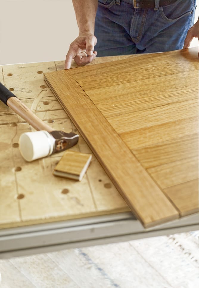 A person inspecting a test panel they made to check before installing a herringbone floor.