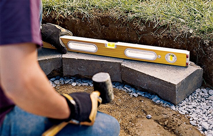 Using a mallet to level the blocks for a fire pit