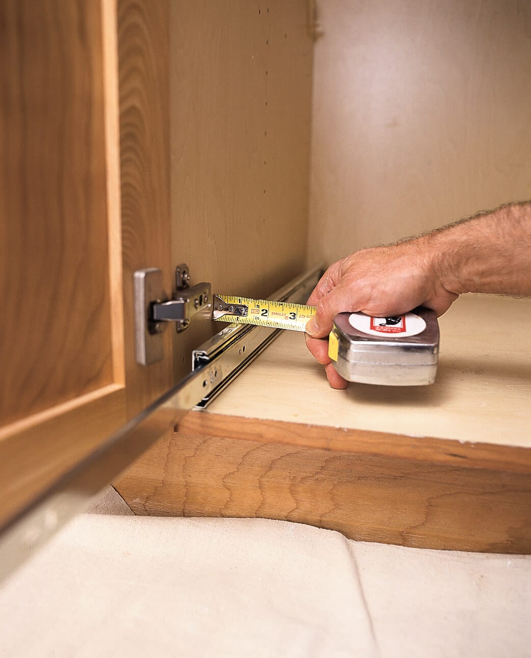 using a tape measure to measure a kitchen cabinet
