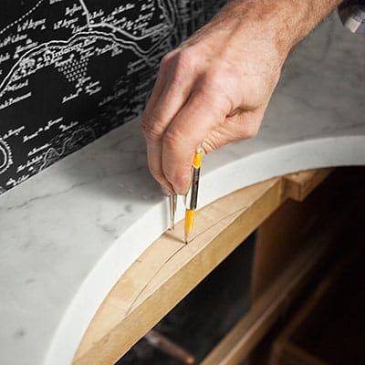 A man marking a piece of wood with a pencil.