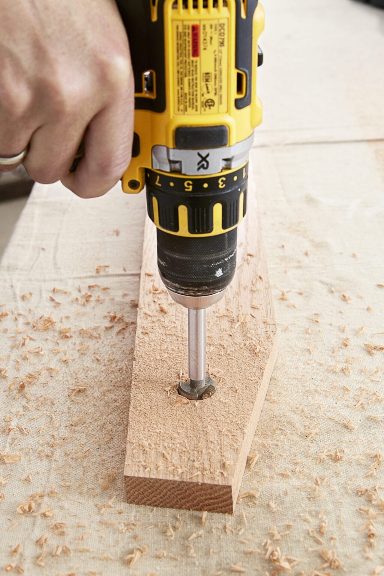 Image of a person completing a step in the DIY rolling library ladder project, which involves creating the spindle hole
