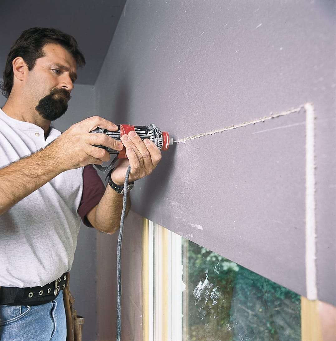 Person trimming drywall around doors and windows
