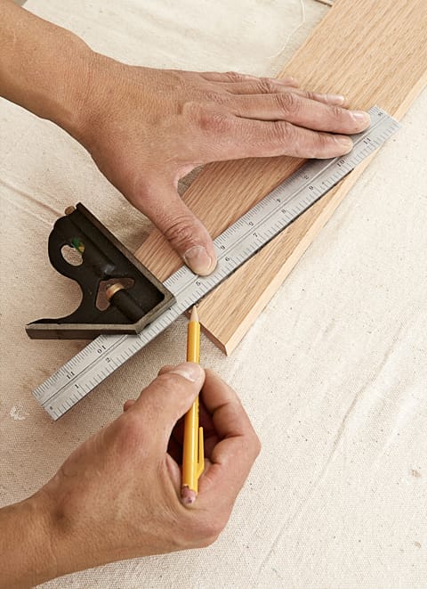 Image of a person completing a step in the DIY rolling library ladder project, which involves shaping the tops of the handrail pieces
