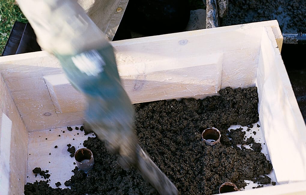 A person packs the hypertufa mix into the trough.