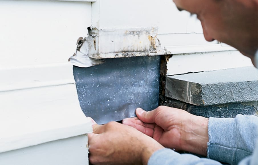 A man installs flashing on his home.