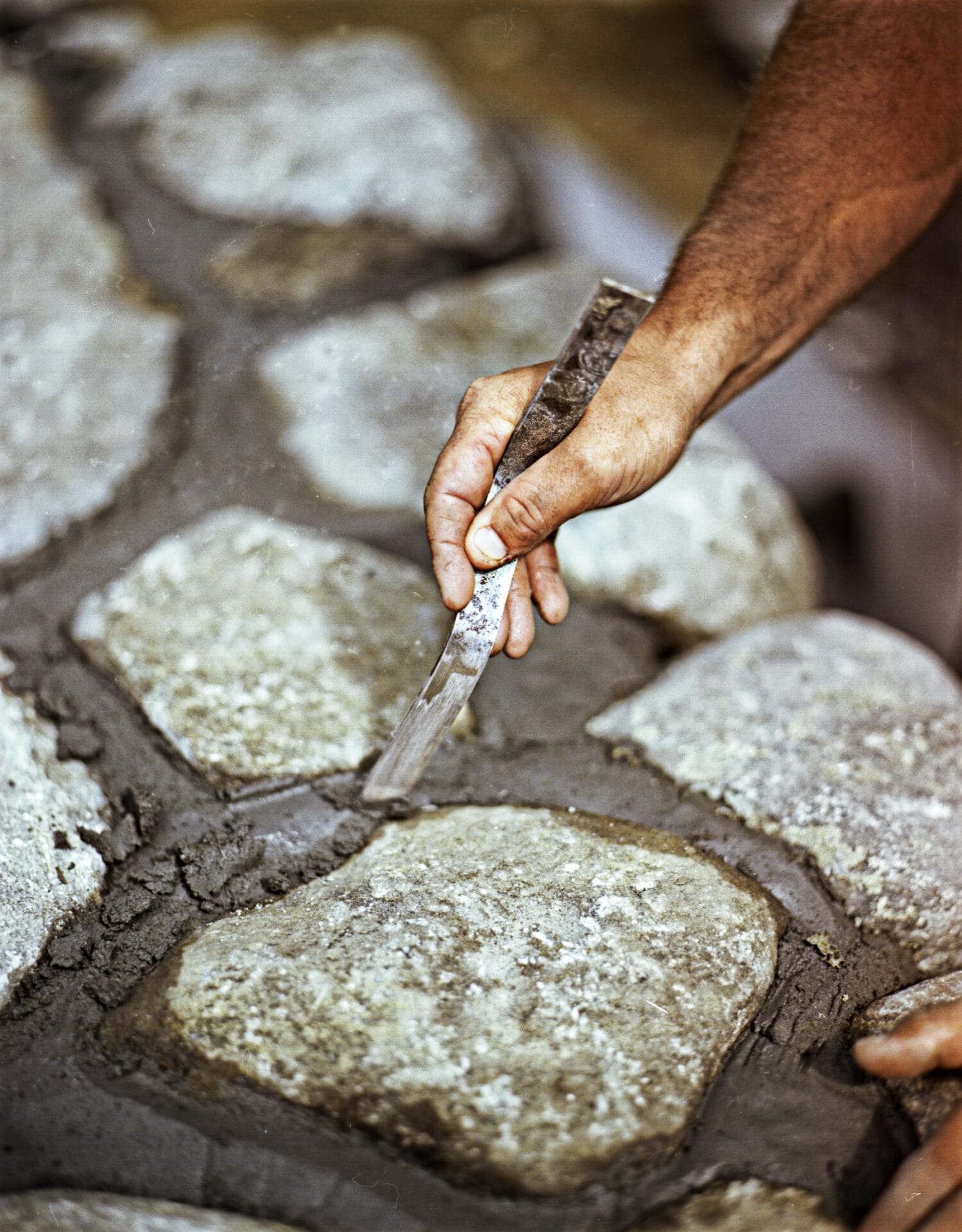 A tool being used to smooth the joints between stones in a wall.