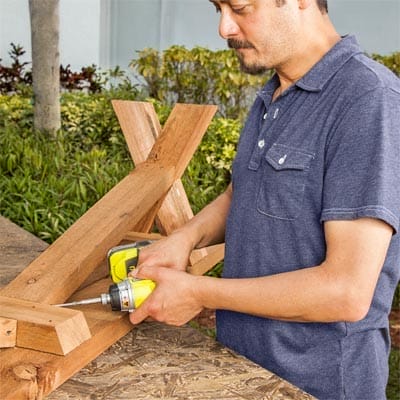 A man makes the seats and legs for a classic picnic bench.