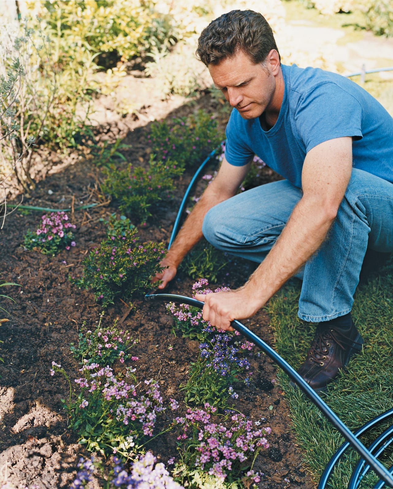A man laying out the main tubing for a drip irrigation system.