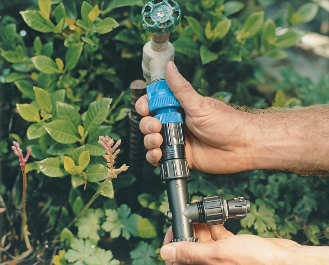 An image of a man connecting to his water source for his drip irrigation.