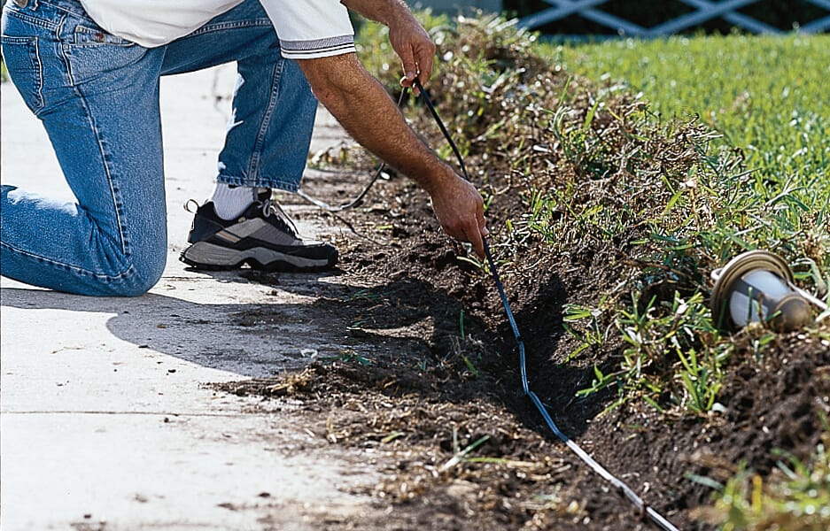 A man buries cables for landscaping lights.