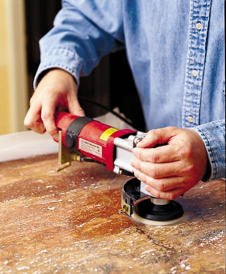 a professional sanding a kitchen countertop to remove stains