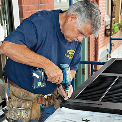A man installs the hinges to his shutters.