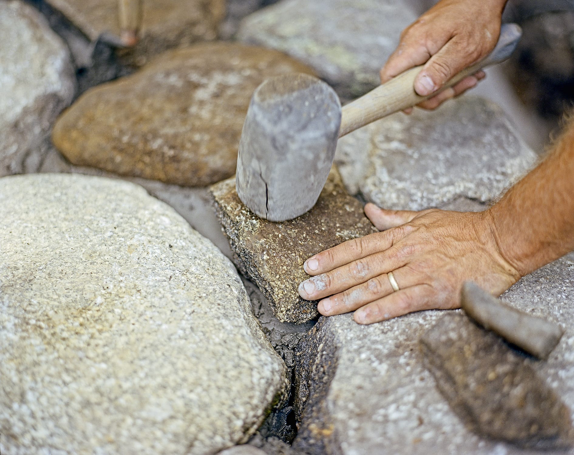 A mallet being used on a stone portion of a wall.