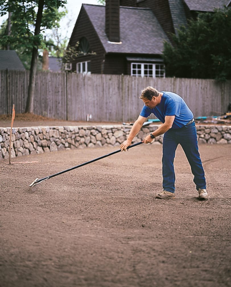 Rodger Cook rakes the soil's surface to prepare it for grass sod.