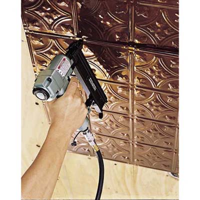 A person using a brad nailer to nail up the first panel. 