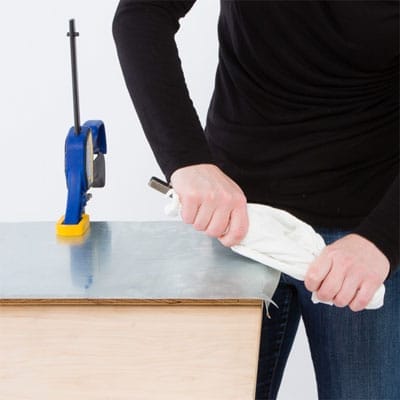 A woman bends the edges of her zinc tabletop.