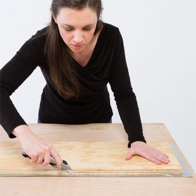 A woman begins cutting the edge of her tabletop.