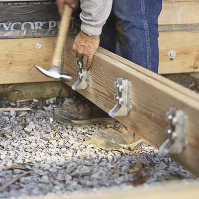 A man using a hammer to build a deck.