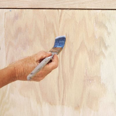 A man applies clear coat over the pickled finish he just applied.
