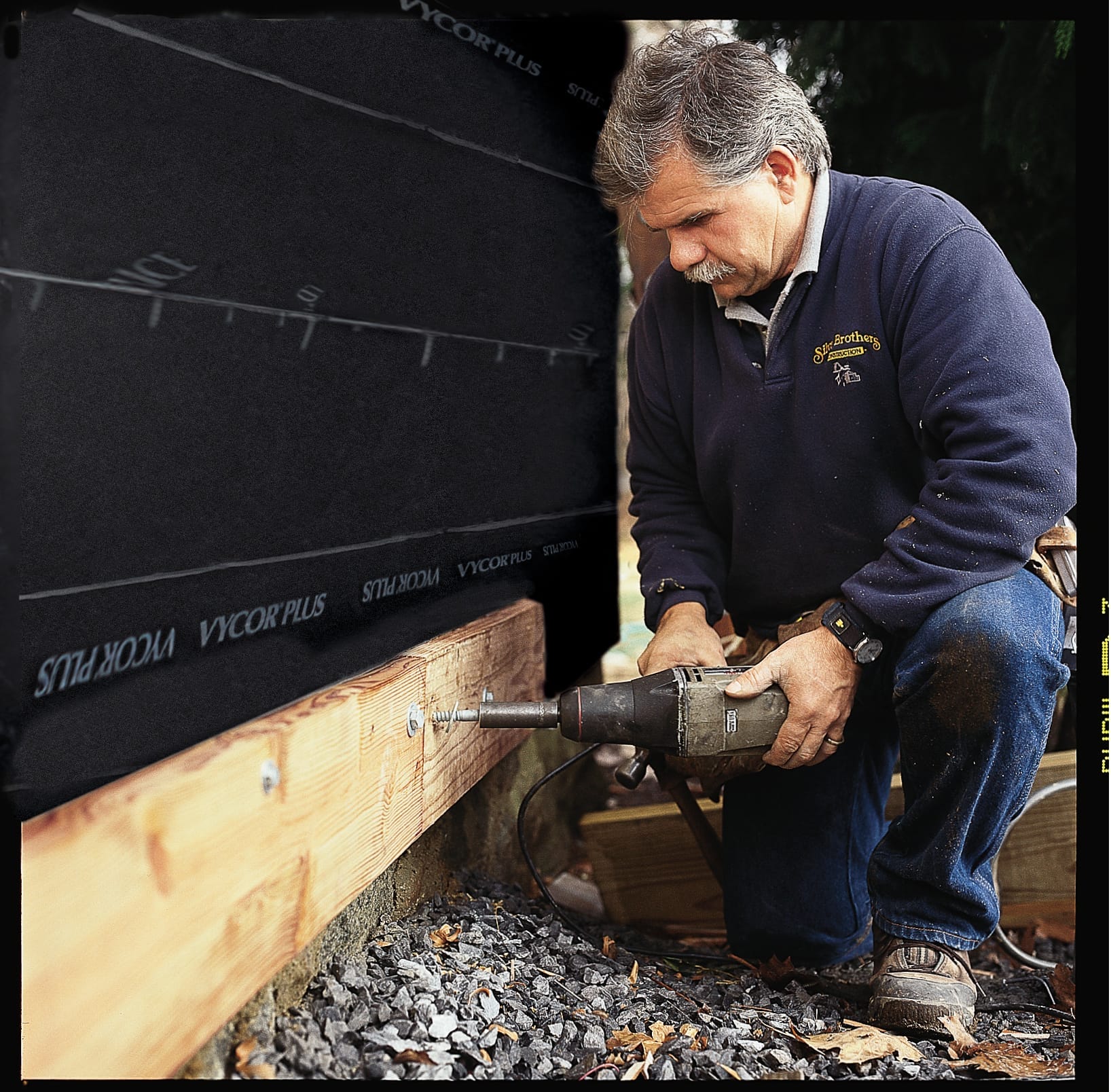 A man using a drill to build a deck.