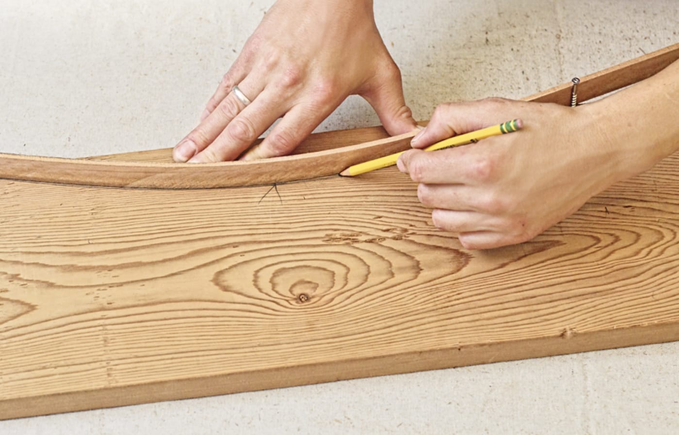 Photo of a person tracing the arm curve of a chair for a Westport chair building project. 