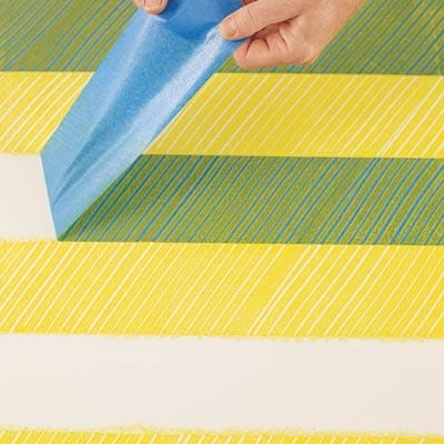 A person using a plastic comb to create a herringbone pattern on a table.