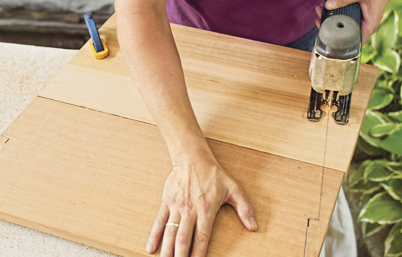 Photo of a person marking cutlines of the backrest of a chair on wood for a Westport chair building project. 