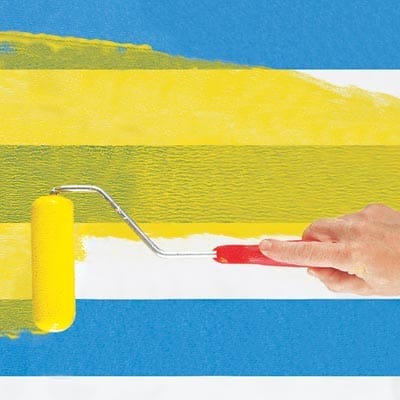 A person painting glaze onto a table for a herringbone pattern.