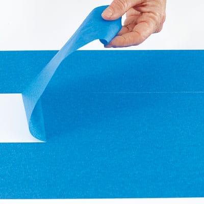 A person applying tape to a table before adding a herringbone pattern.