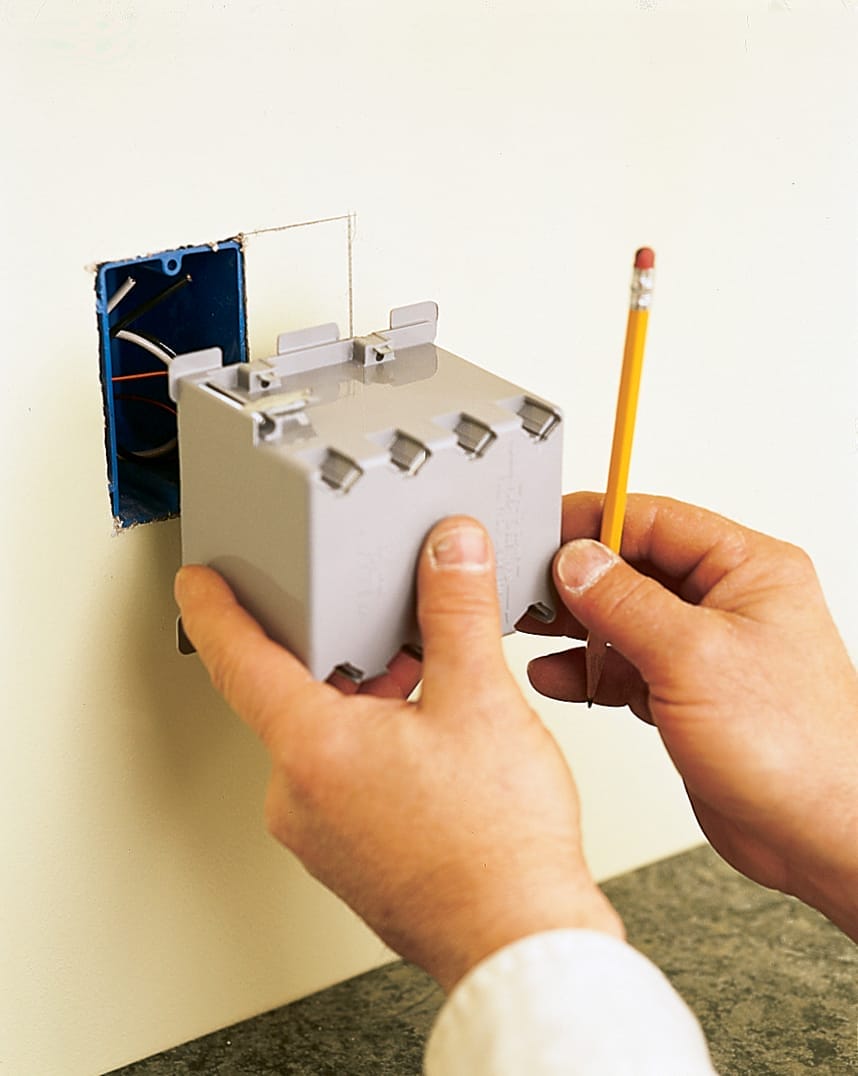 A person traces the outline of a new electrical box.