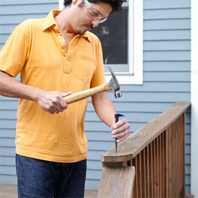 A man hammering a deck railing.