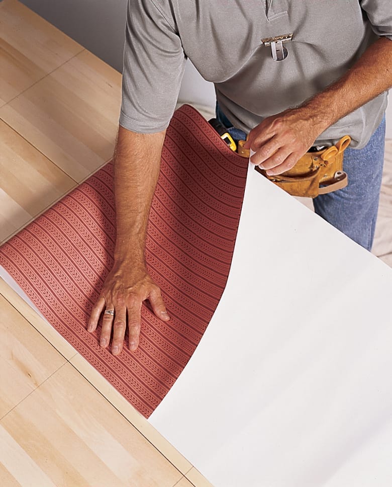 A man books the wallpaper to prepare it to be hung.