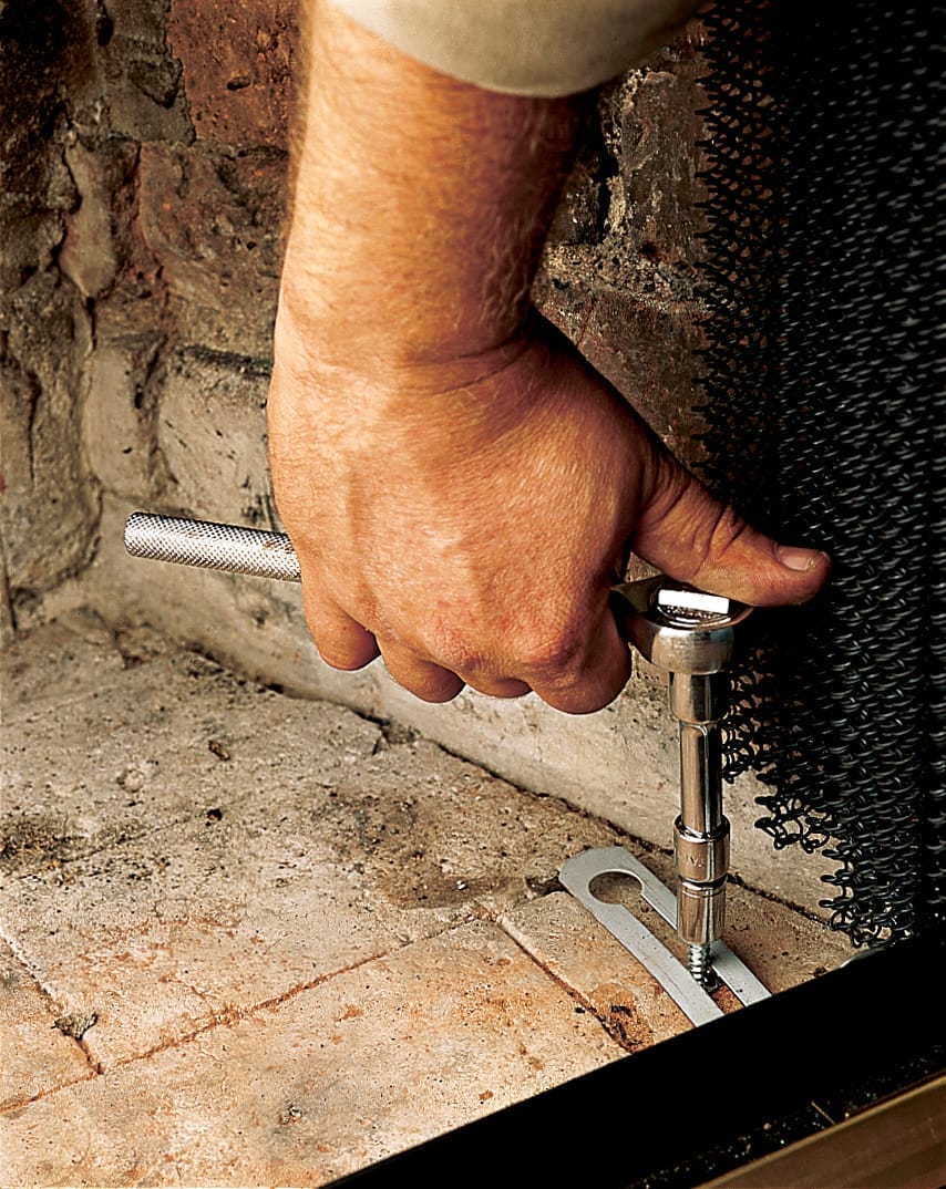 A man screws the door to the firebox floor.