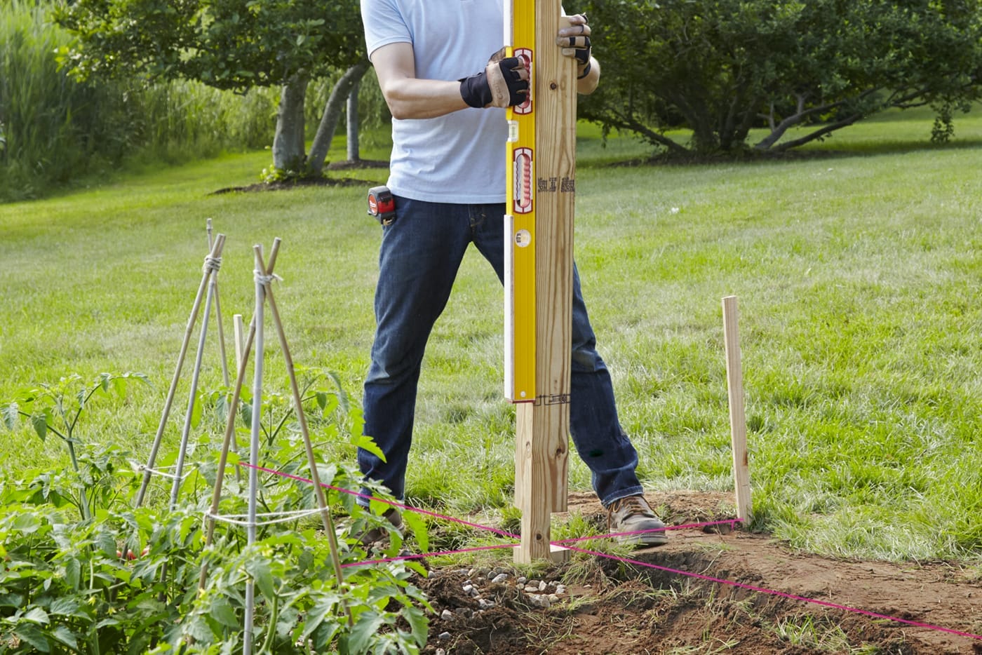 A person sinking the first post for a garden fence.