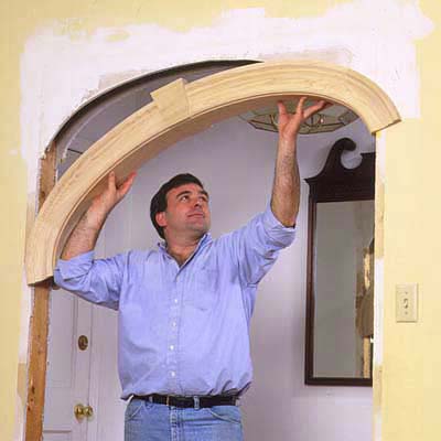 A man lifts the elliptical archway into place and secures the prefab arch.