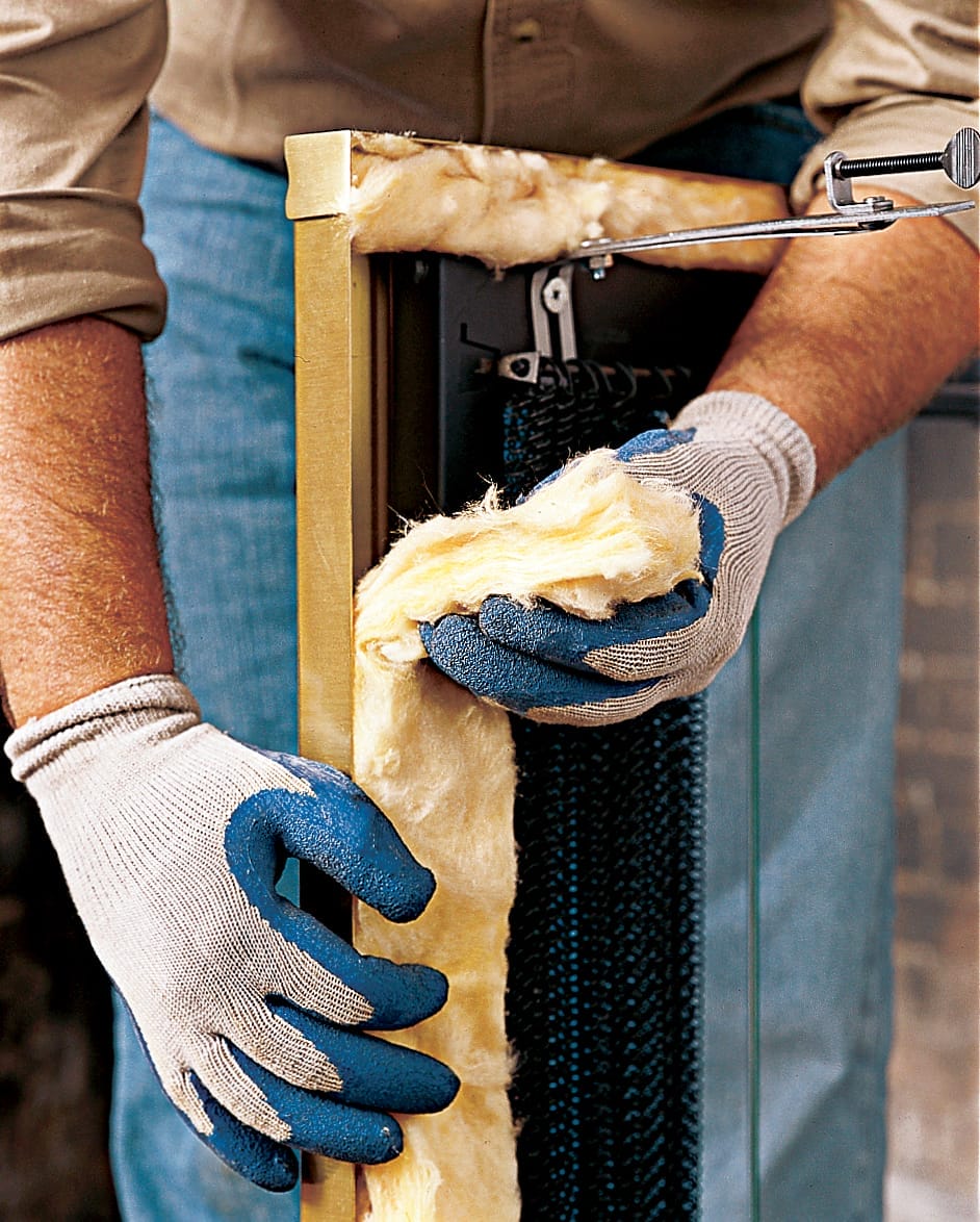 A man insulates his glass fireplace doors.