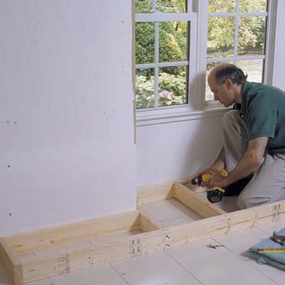 A man using a drill to ready a space to install a cabinet.