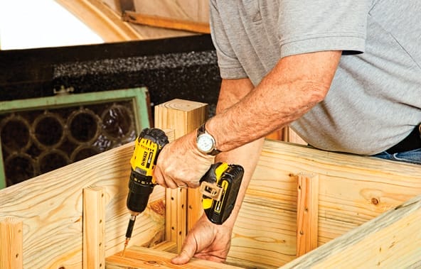 Man using drill to install floorboards