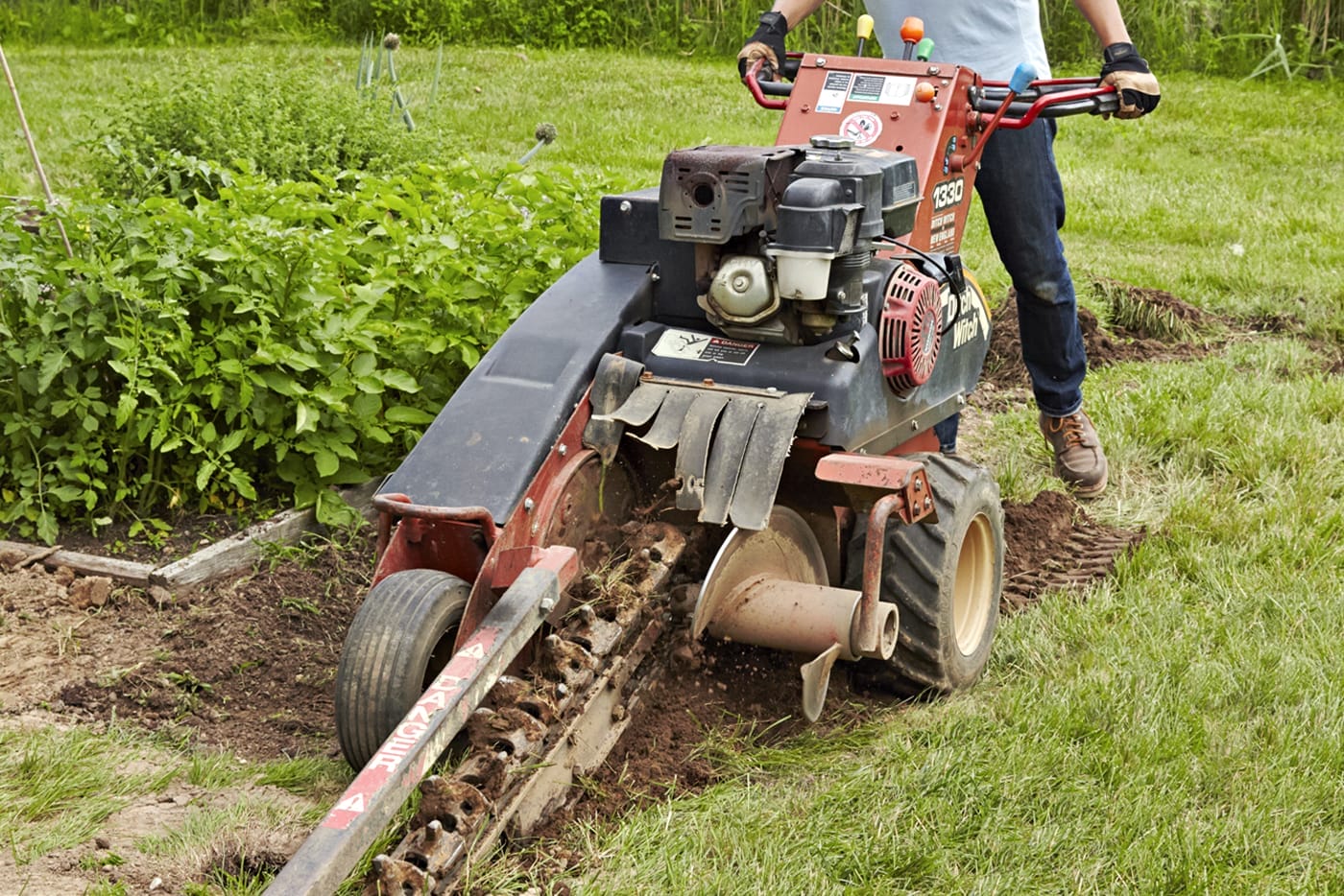 A person digging trenches for a garden fence.