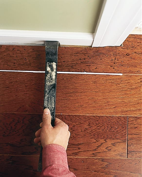 using a tool to move the floating floor away from the wall