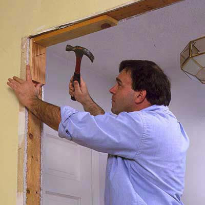 A man installs nailing blocks into the top of the doorway where the corners will become an archway.